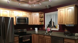 Una cocina moderna con armarios de madera, electrodomésticos de acero inoxidable y un ventanal con cortinas.