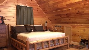 Un dormitorio de cabaña de madera con cama, tocador y perchero.