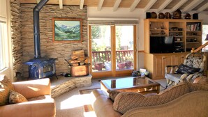 A cozy living room with a stone wall, a fireplace, a sofa, a coffee table, and a bookshelf.