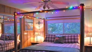 A bedroom with a canopy bed, a ceiling fan, and string lights.
