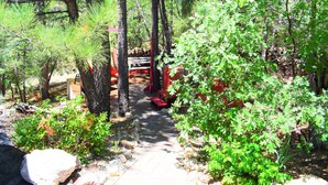 A forested path with a wooden bench and a red structure.