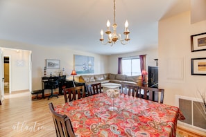 Uma área de refeições com toalha de mesa estampada, um candelabro e um sofá ao fundo.