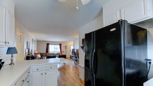 A spacious kitchen with white cabinetry, a black refrigerator, and a dining area with a table and chairs.