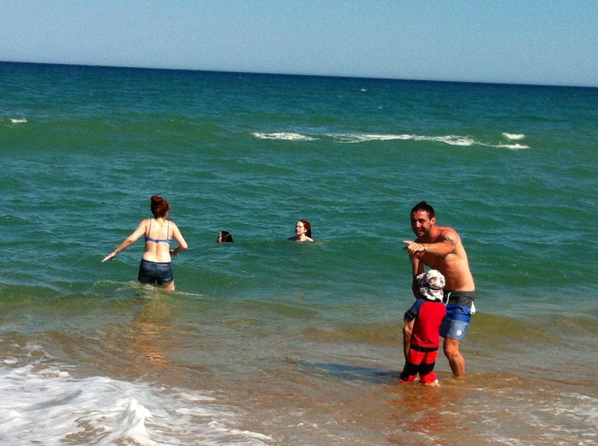 Une scène de plage avec des personnes dans l’eau et sur le rivage.