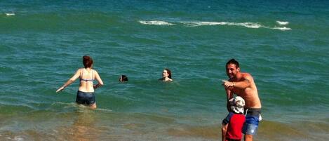 Une scène de plage avec des personnes dans l’eau et sur le rivage.