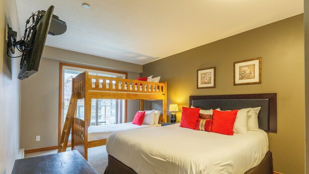 A hotel room with a bunk bed, a desk, and a large window. - Aspen #458 Prime Ski-in Ski-out Location! Pool, Hot tubs, BBQ, sleeps 8 (Whistler)