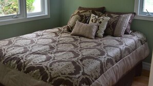 A bedroom with a large bed, two windows, and a ceiling fan.