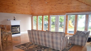 A spacious living room with a fireplace, large windows, and a view of the outdoors.