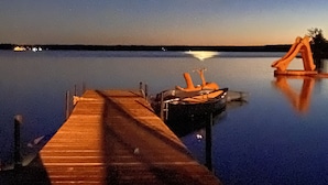 A wooden dock extending into calm water with a boat docked at the end.