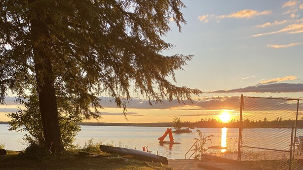 A wooden deck with a view of a lake and sunset.