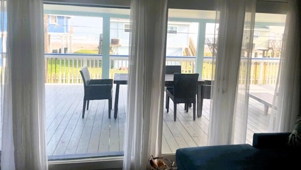 A room with a view of a wooden deck and outdoor furniture.