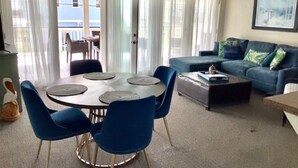Ein Wohnzimmer mit rundem Tisch, blauen Stühlen, einer Couch und einem Couchtisch.