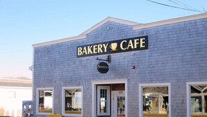 Eine Bäckerei-Café mit einem Schild, auf dem 'BAKERY CAFE' steht, und einer herzförmigen Bank draußen.