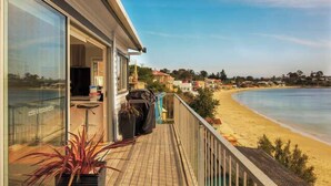 Une propriété située en bord de mer, dotée d’un balcon donnant sur la plage, avec un ciel dégagé et une vue sur l’océan.