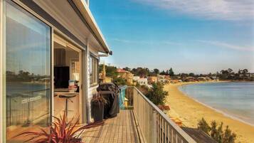 Enjoy stunning ocean views from this beachfront property's spacious balcony, featuring a seating area with a table and chairs.