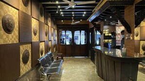 A restaurant interior with a bar area, seating, and a view through the windows. - Hotel Kailash (Birgunj)