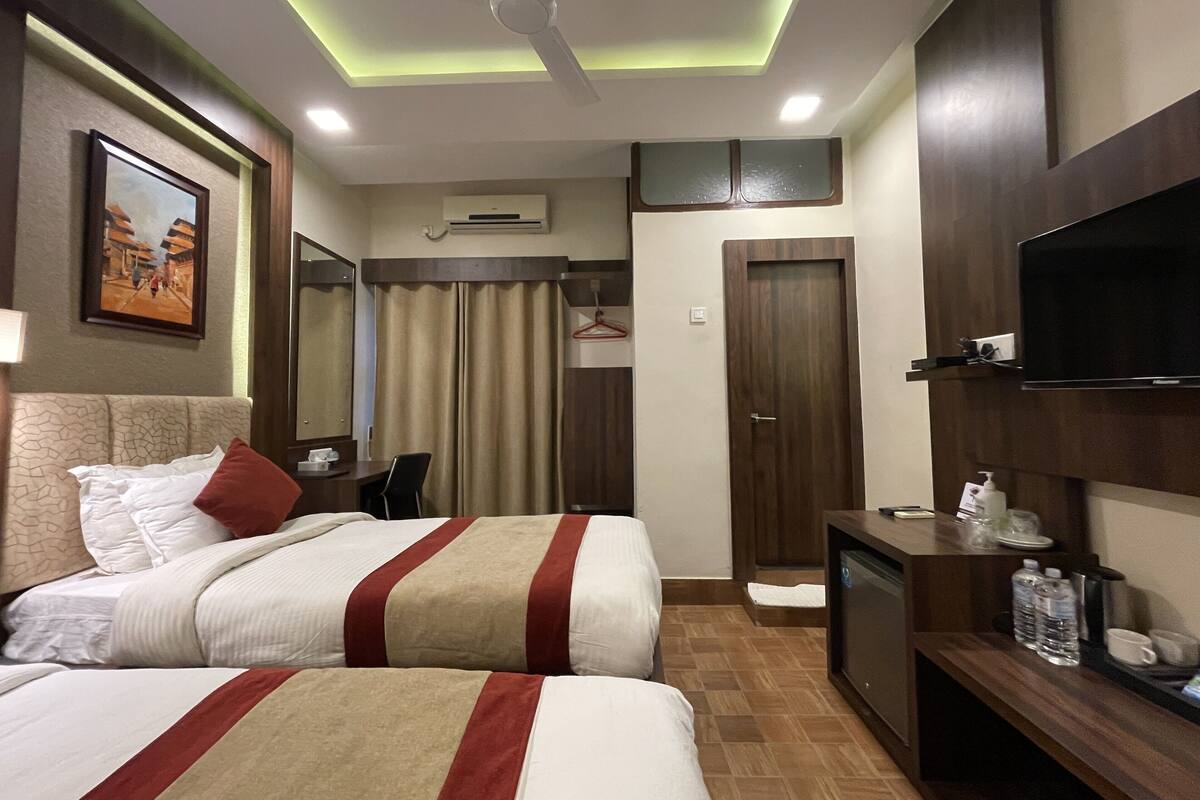 A hotel room with two beds, a desk, a television, and a wardrobe.