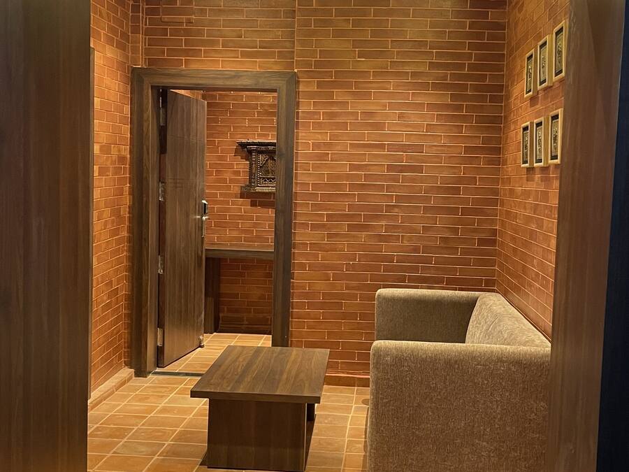 Un interior moderno con pared de ladrillo, un sofá, una mesa de centro y una puerta que da a otra habitación.