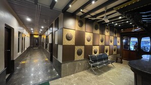 A hotel lobby with a long corridor, a reception desk, and a seating area with a bench. - Hotel Kailash (Birgunj)
