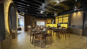 A restaurant with a bar area, wooden chairs, and a tiled floor. - Hotel Kailash (Birgunj)