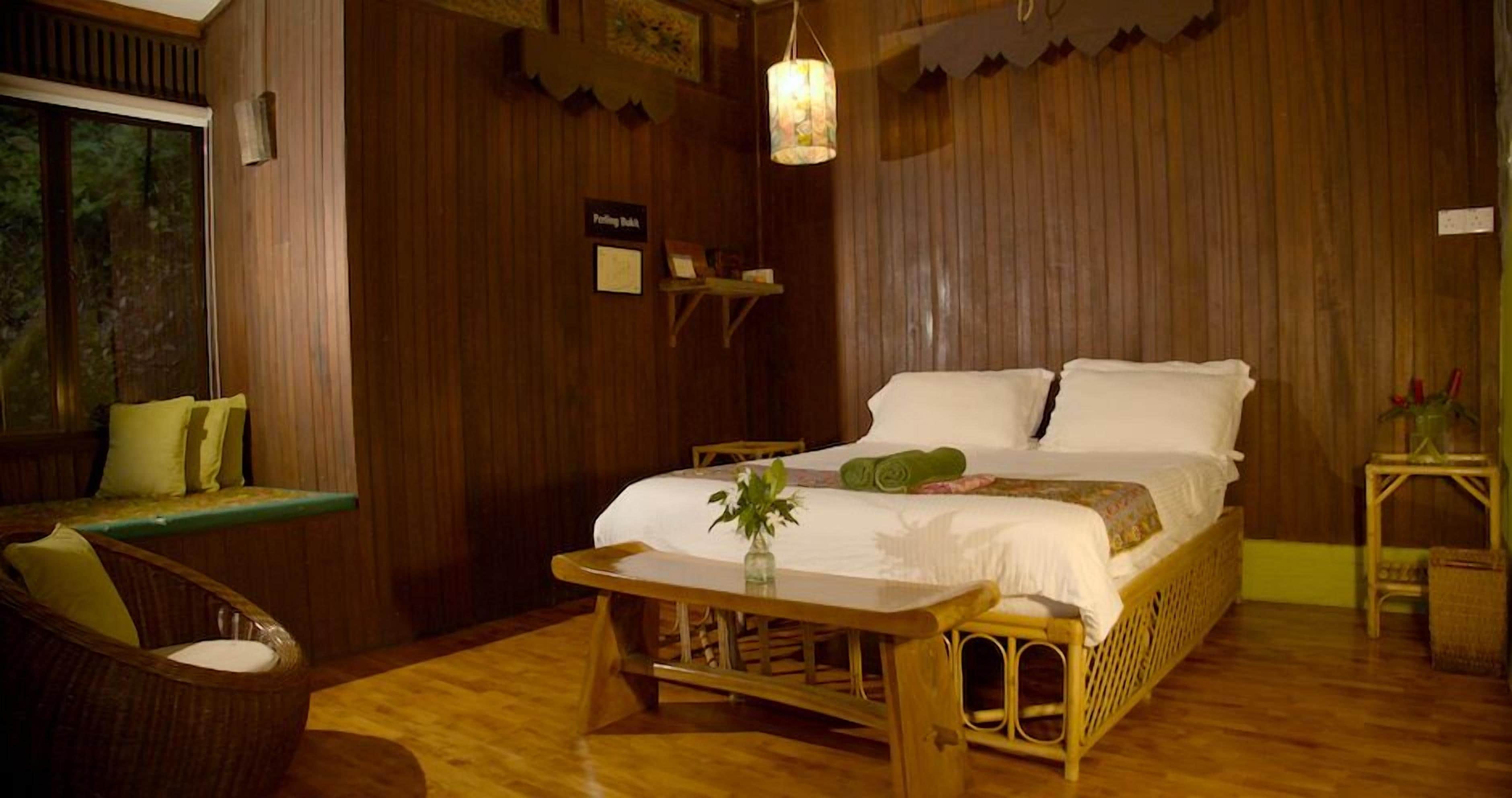 A wooden room with a bed, a small table, and a bench.