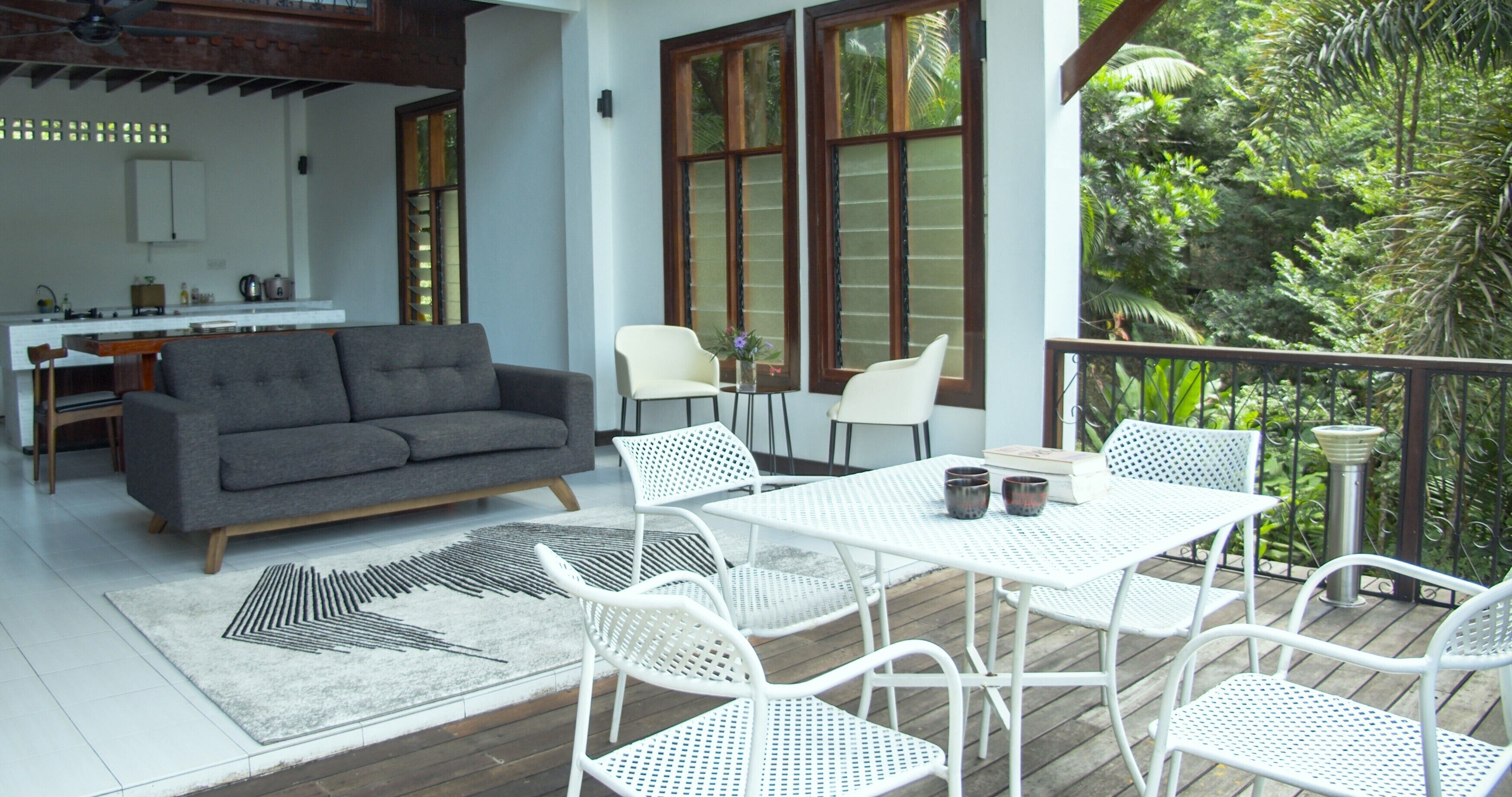 Un salón moderno con un sofá gris, sillas blancas, una mesa blanca y una alfombra estampada.