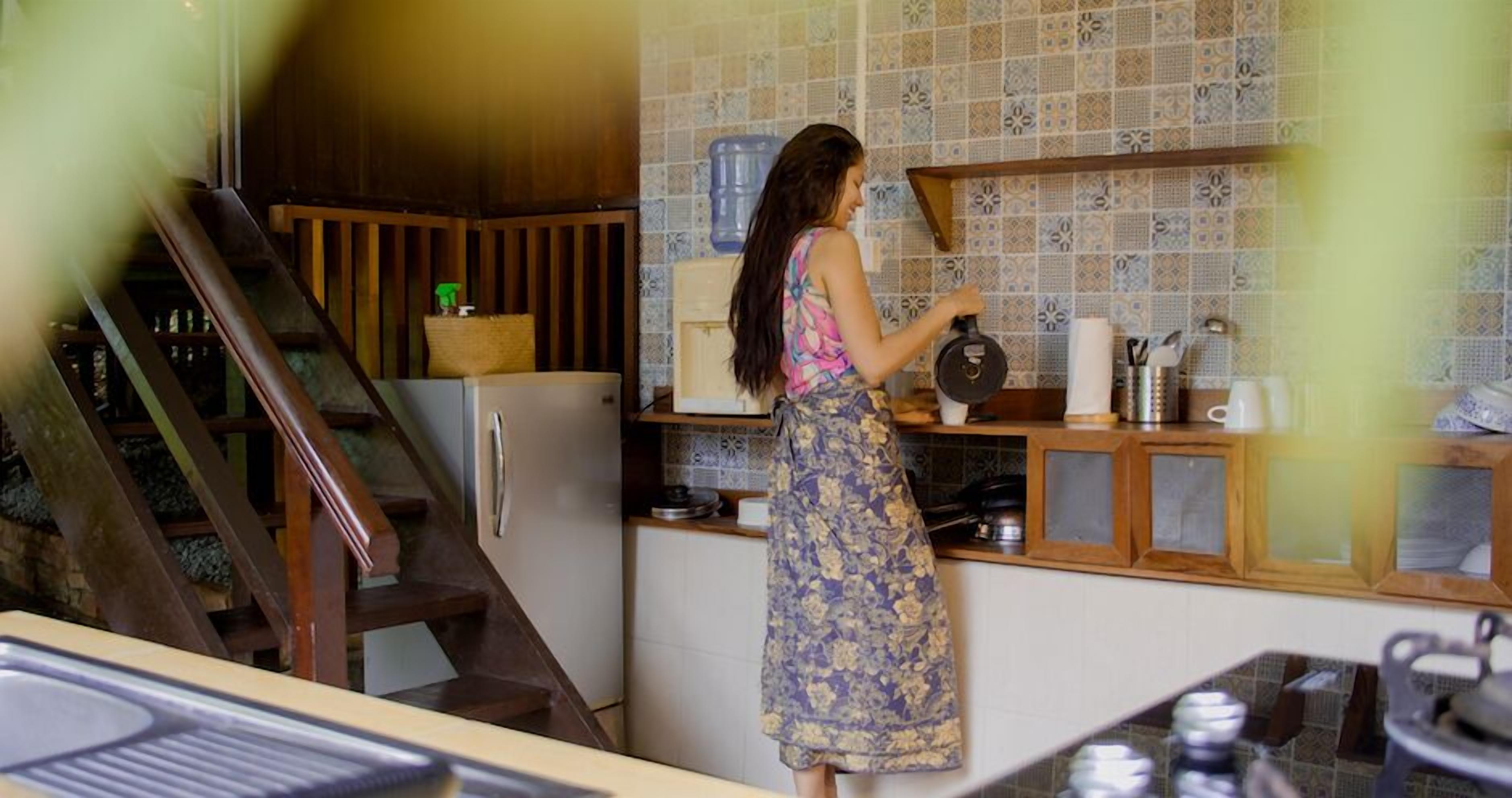 Uma cozinha com escada de madeira, dispensador de água e painel de azulejos.