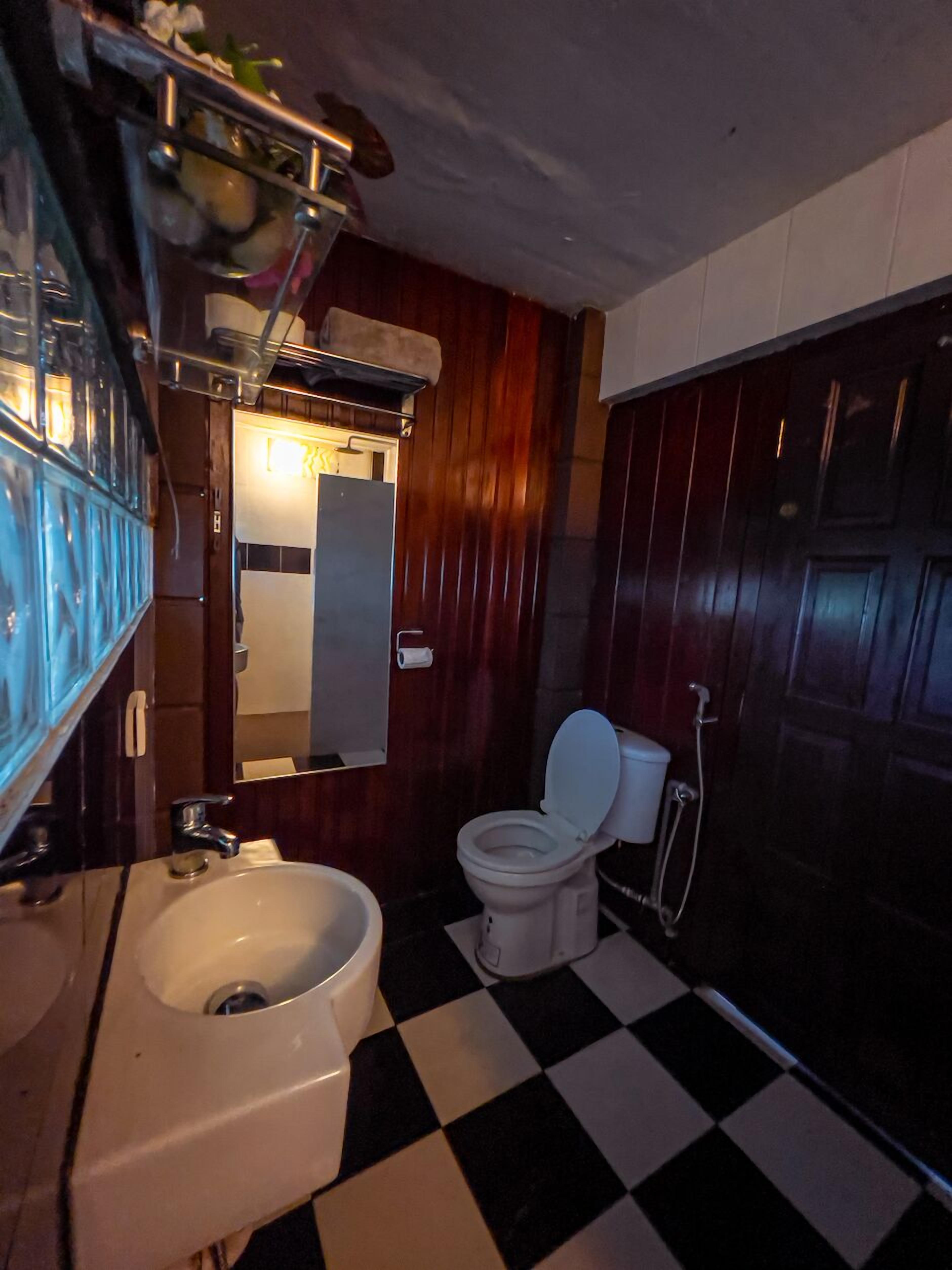 A bathroom with a checkered floor, a white toilet, a sink, and a mirror.