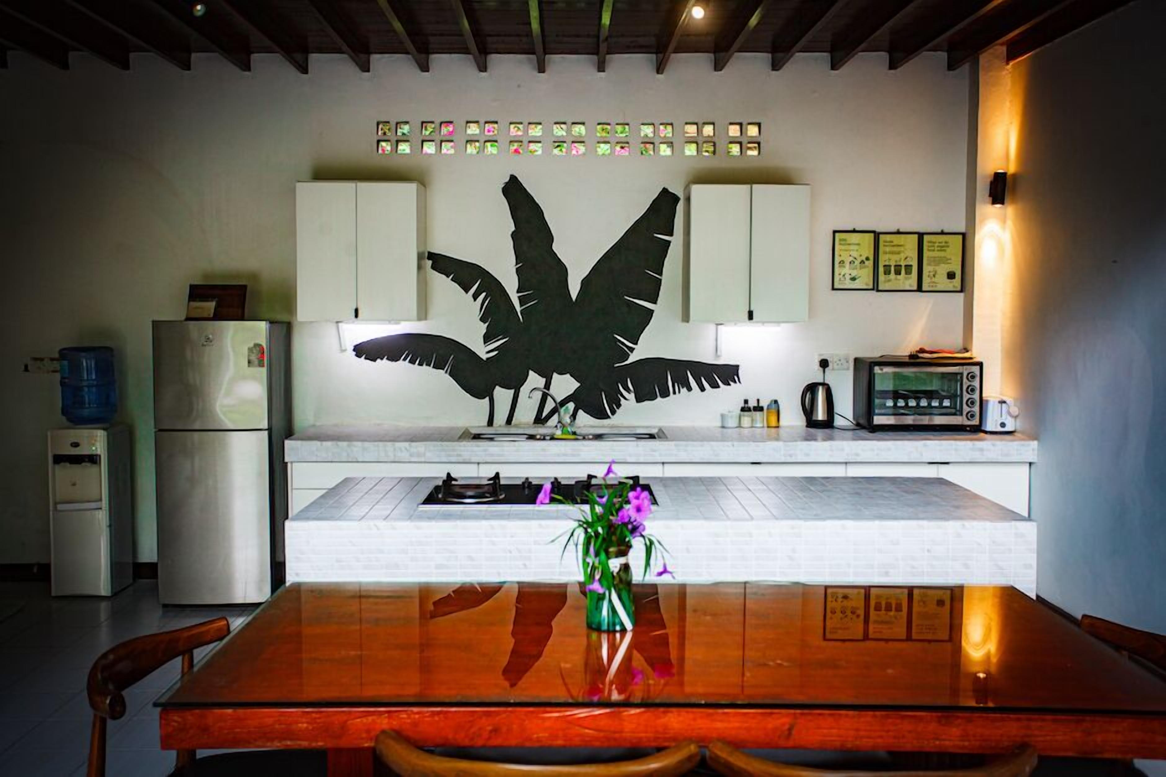 A kitchen with a large black bird mural, a refrigerator, a stove, and a coffee maker.