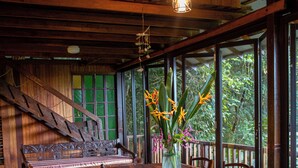 Un coin repas en bois avec une grande table, des chaises, un banc et un vase rempli de fleurs.