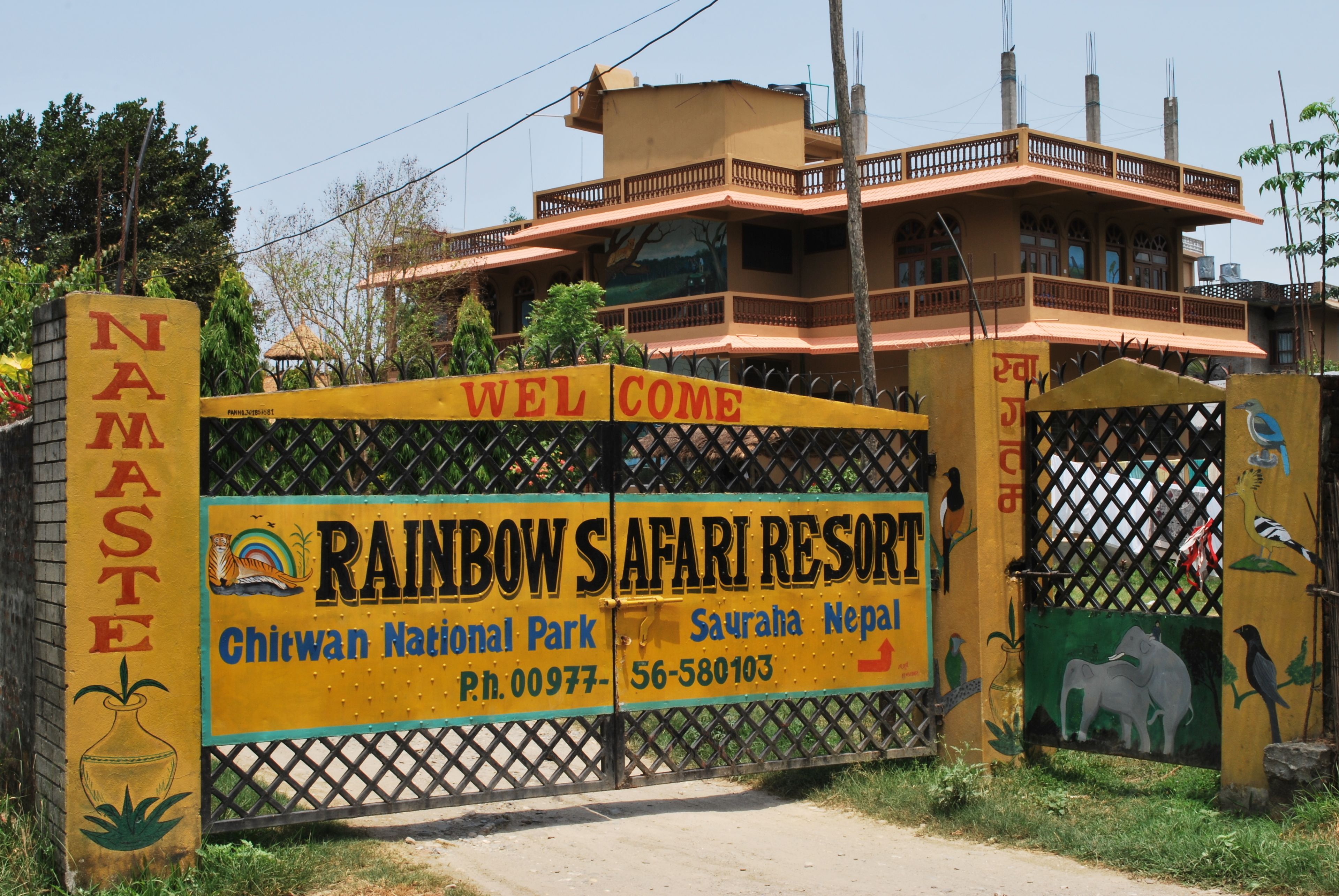 A sign for Rainbow Safari Resort with a welcome message, contact number, and location details.