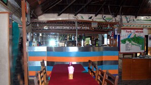 A restaurant with a colorful striped wall, a bar area, and a table with chairs. - Rainbow Safari Resort (Sauraha)