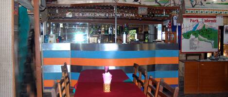 A restaurant with a colorful striped wall, a bar area, and a table with chairs.
