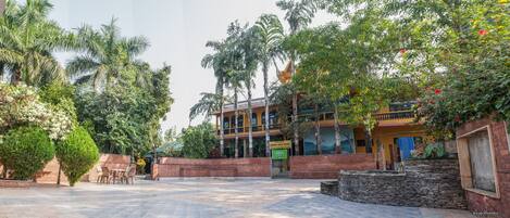 A courtyard with a building, palm trees, and a sign for a safari resort.