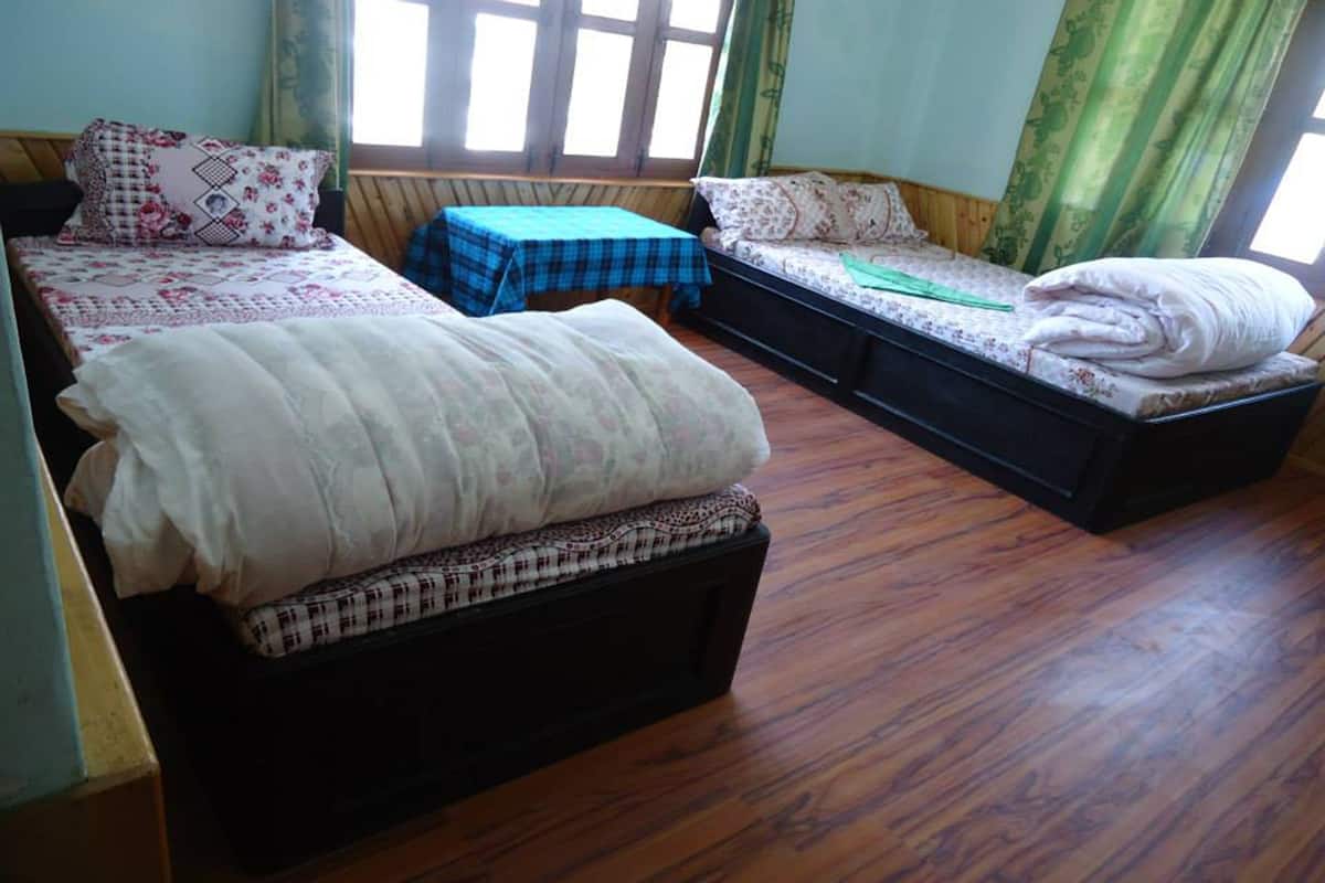 A room with two beds, a small table, and a window with curtains.