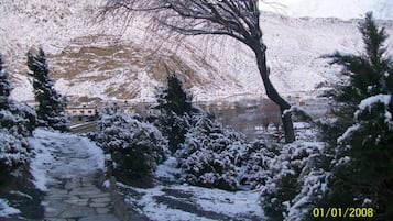 A snow-covered stone pathway leading to a building with a mountainous backdrop.