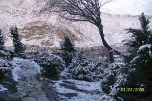 Un sendero de piedra cubierto de nieve que lleva a un edificio, con montañas al fondo.