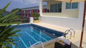 A swimming pool with blue tiles, a sun umbrella, and a lounge chair. - Living Residence Phuket (Wichit)