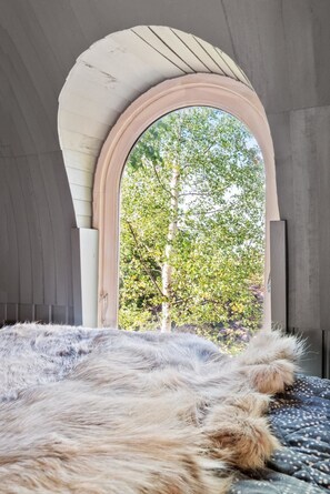 A bedroom with a large window, a fur rug, and a wooden headboard. - Villa Heidi (Stange)