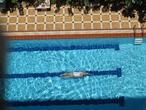 Ein Schwimmbecken mit klarem, blauen Wasser, markierten Bahnen und einer mit Schachmuster belegten Wand.