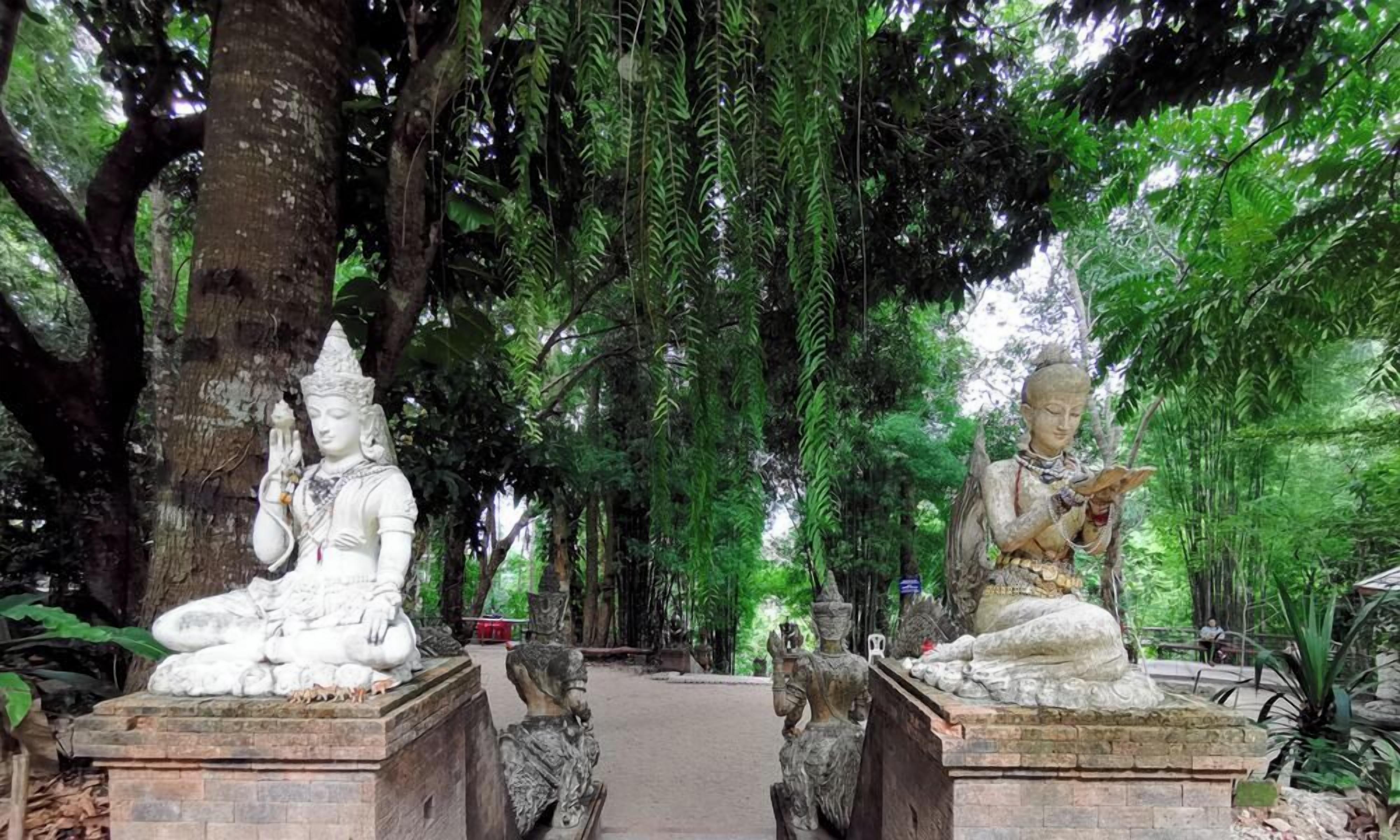 A serene temple setting with large trees and stone statues.