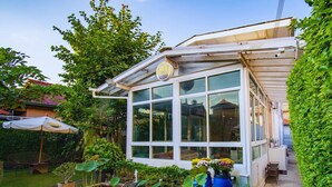 A conservatory with a glass roof, surrounded by lush greenery and a small pond with water lilies. - Hostel Lullaby - Adults Only (Chiang Mai)