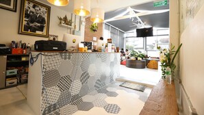 A reception area with a patterned counter, pendant lighting, a framed photograph, and a fire exit sign. - Hostel Lullaby - Adults Only (Chiang Mai)