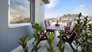 Un patio al aire libre con una mesa y sillas, rodeado de plantas en macetas.
