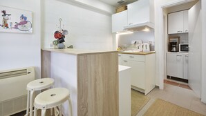 Una cocina moderna con armarios blancos, encimera de madera y una pequeña isla con taburetes.