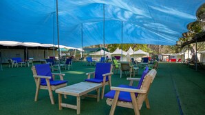 A covered outdoor seating area with wooden chairs and tables, surrounded by tents. - The Camping Site Hamat Gader (Hamat Gader)