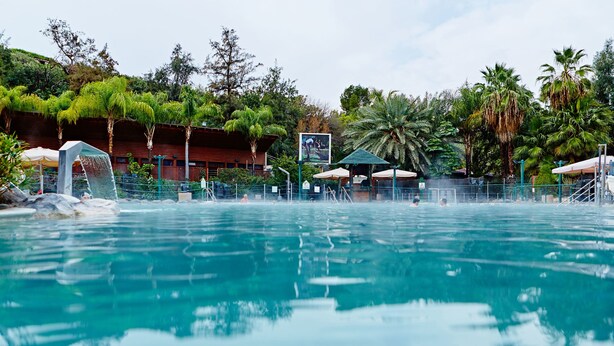 A swimming pool with a view of a building and trees in the background. - The Camping Site Hamat Gader (Hamat Gader)
