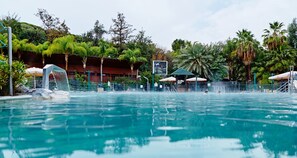 Uma piscina com vista para um edifício e árvores ao fundo.