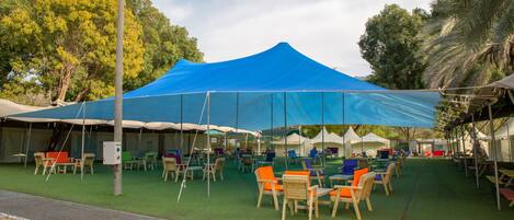 A campsite with tents and tables, surrounded by greenery.