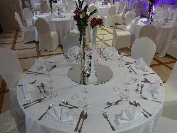 A banquet hall with round tables set for a formal event, complete with white tablecloths, silverware, and floral centerpieces. - Qasr Al Sahab (Khamis Mushait)
